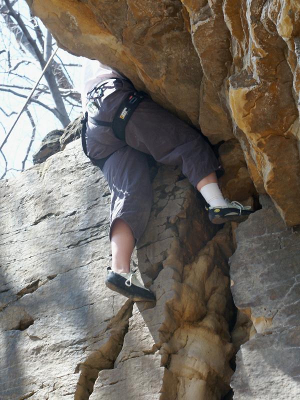 The rock face swallows Karen from the waist up
